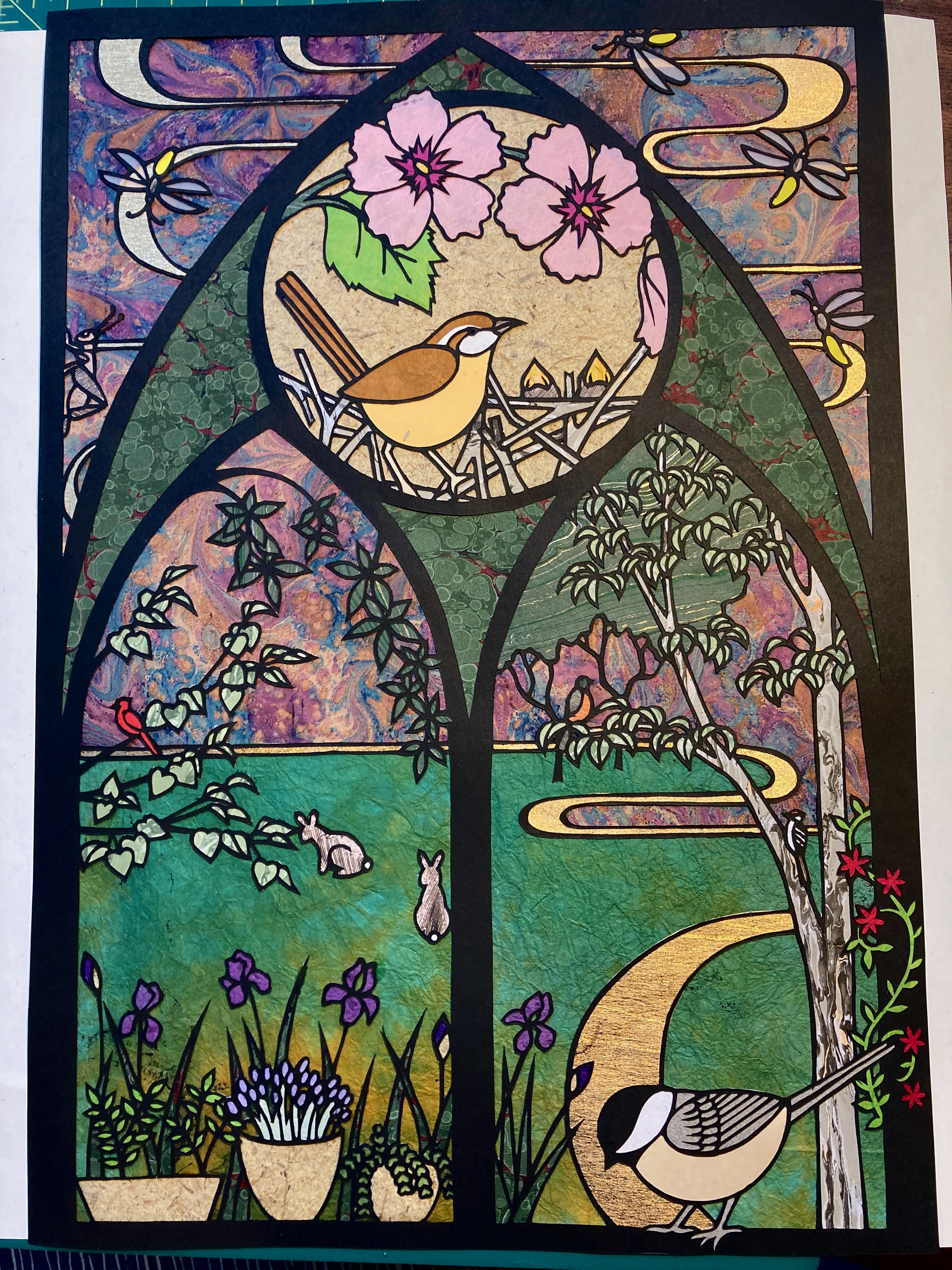 Gothic cathedral window paper cut with nesting bird, cherry blossoms, chickadee, and rabbits